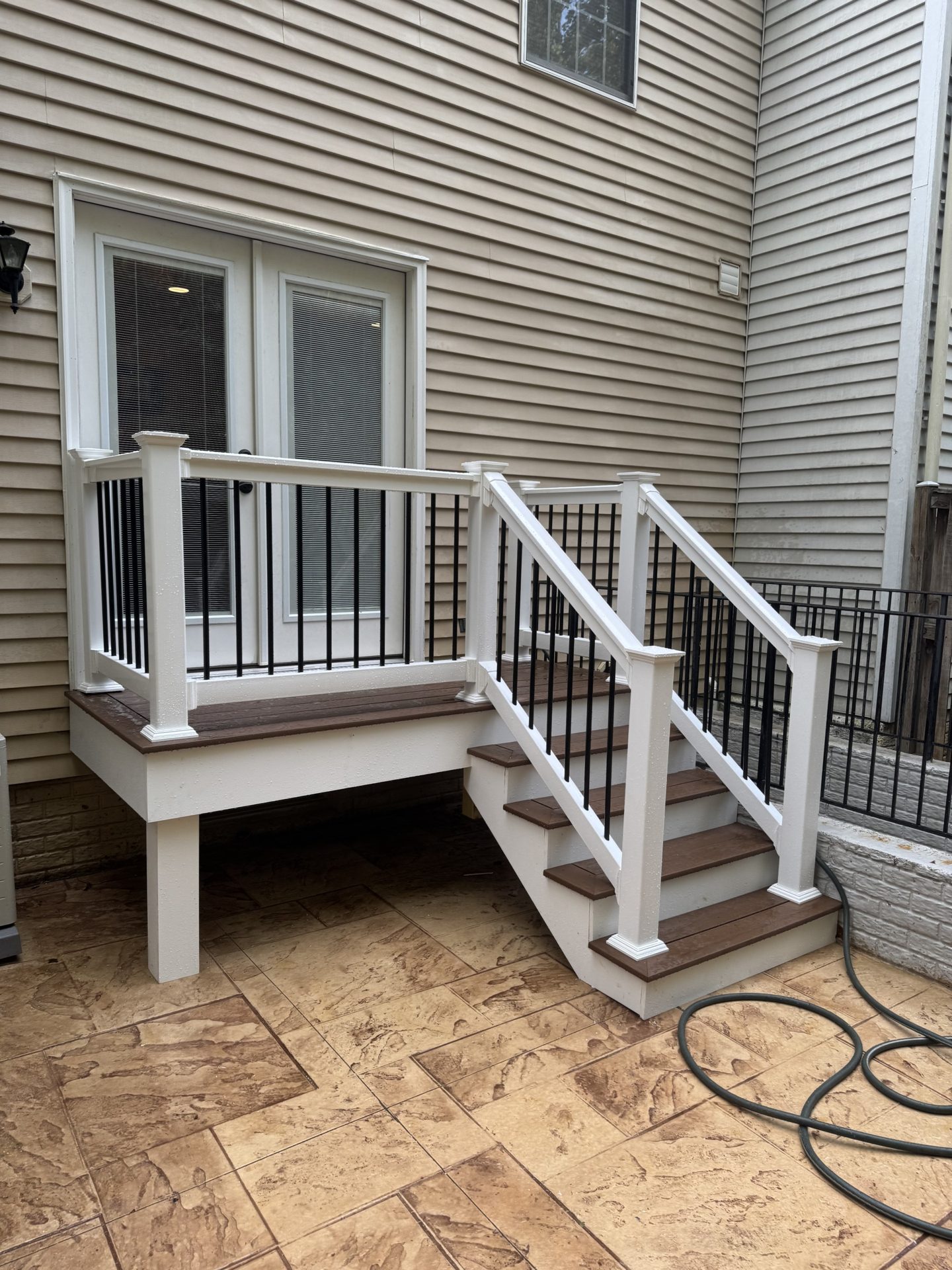 Deck entry stairs with white railing and black balusters in Grasonville, MD — Assured Contracting Company