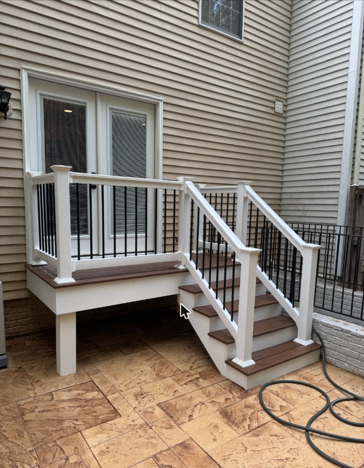 Deck stairs with white railing and black balusters in Grasonville, MD — Assured Contracting Company