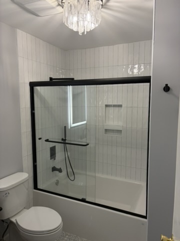 Bathtub with matte-black framed sliding glass doors and white subway tile surround in Grasonville, MD — Assured Contracting Company