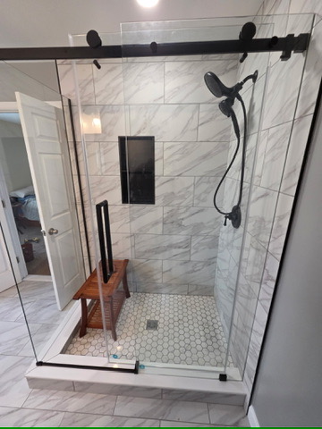 Walk-in glass shower with marble-look tile and teak bench in Grasonville, MD — Assured Contracting Company